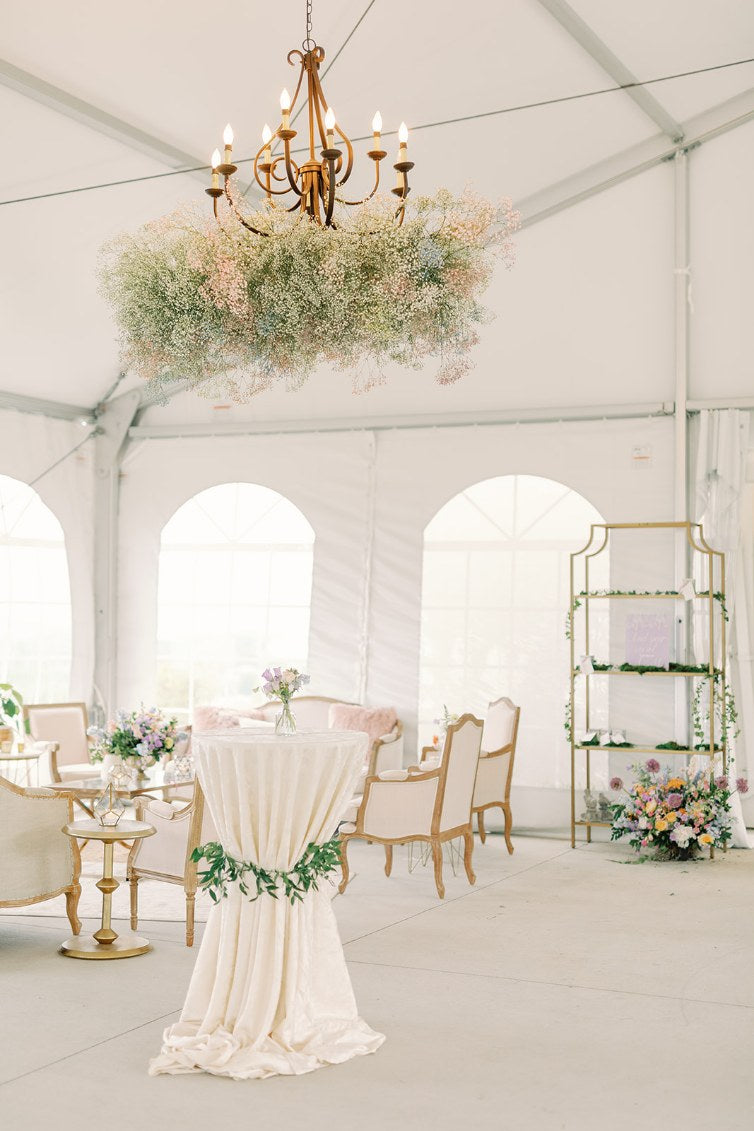 Bridgerton wedding décor at Hershey Gardens with vintage furniture, floral chandelier, calligraphy escort cards, and white linen cocktail tables with greenery in Hershey, Pennsylvania.