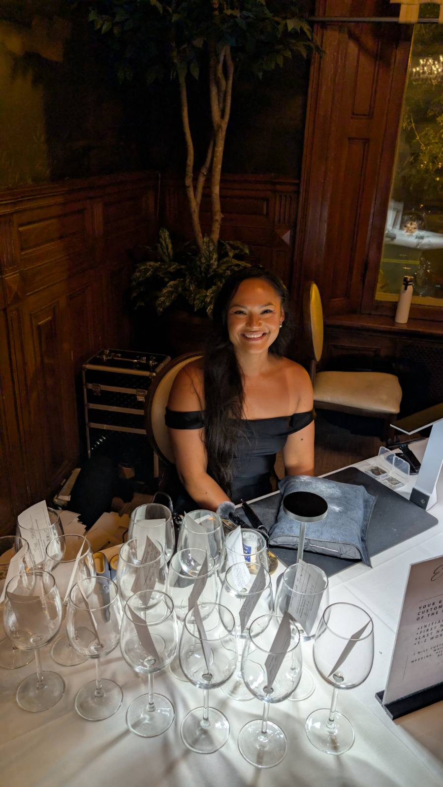 Tiffany Bauer of SLM & Design Co. performing live engraving on wine glasses as guest favors at a wedding at The Belvedere in Baltimore, Maryland.