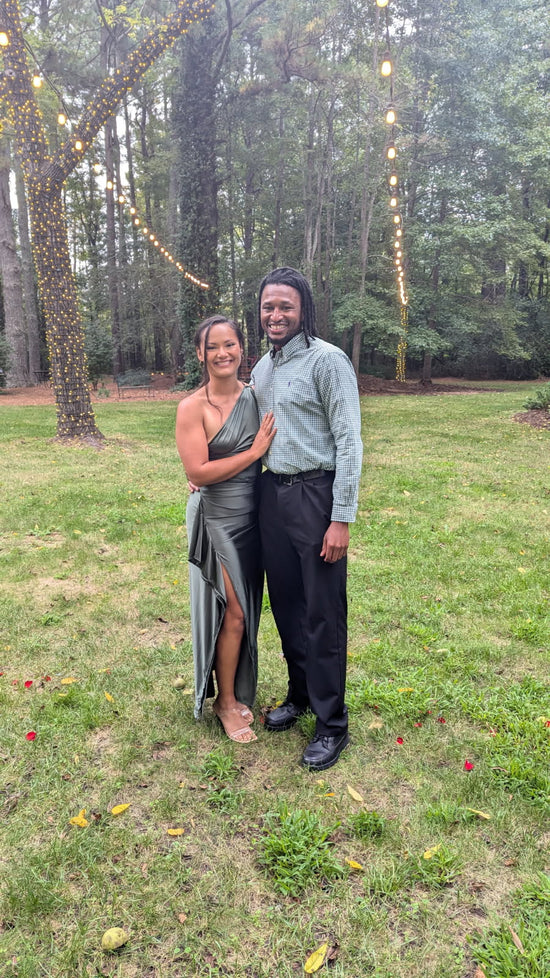 Tiffany, calligrapher, and her fiancé dressed in formal attire at an outdoor wedding ceremony at Country Villa Weddings and Events in Virginia Beach, VA, surrounded by string lights and lush greenery.
