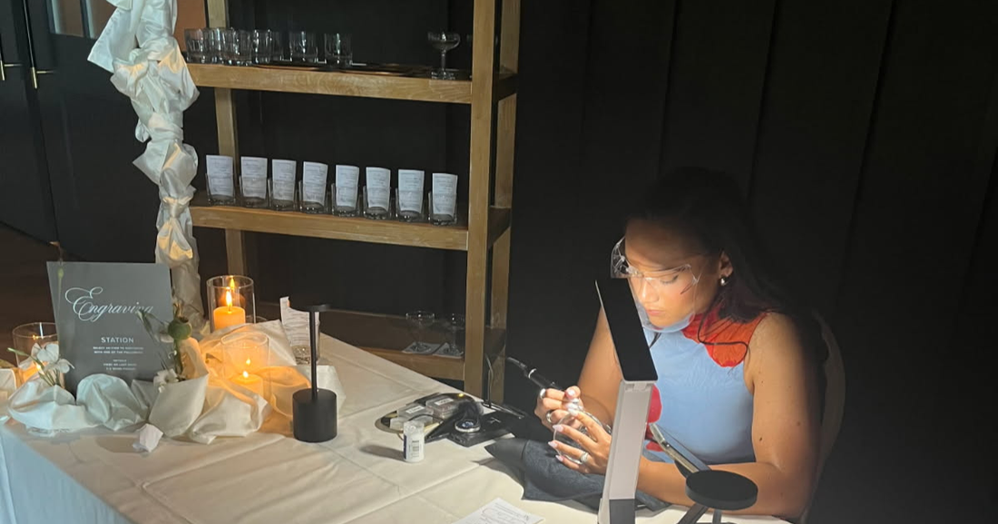 Live wedding engraving on glassware during a wedding reception at The Ivy at Ellis Preserve in Philadelphia, PA. Tiffany of SLM & Design Co. personalizes guest keepsakes with elegant, hand-engraved details.