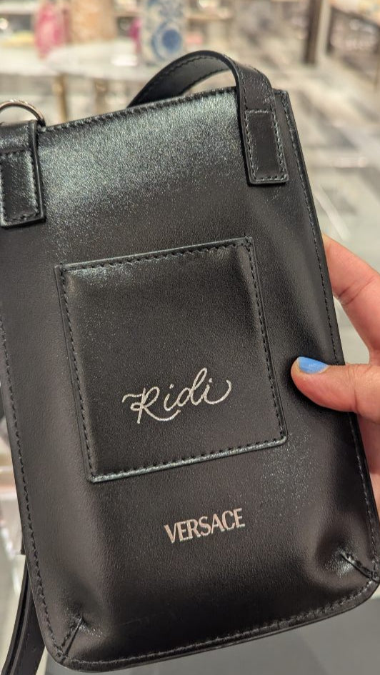 Personalized black leather Versace bag with silver foil name 'Ridi' created during a live heat foiling event at Versace in King of Prussia, PA. Part of a luxury brand Mother’s Day activation featuring custom leather personalization for guests.