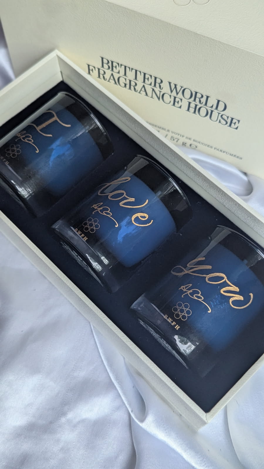 Better World Fragrance House three-piece votive candle set featuring Carbon Musk, Sweeter Tings, and Williamsburg Sleepover. Each candle is hand engraved with gold fill reading 'I love you' as a personalized birthday gift from a wife to her husband.