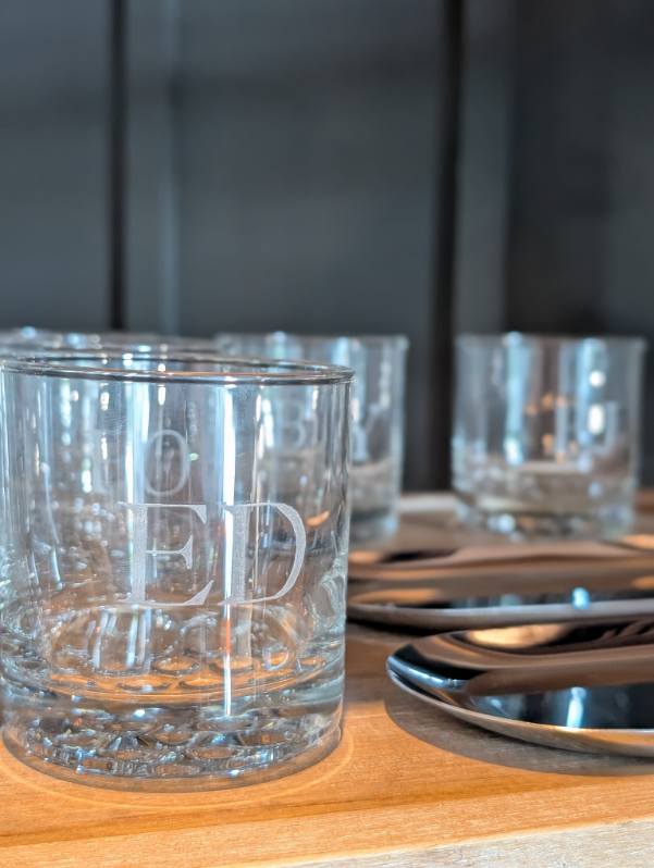 Hand engraved whiskey glass personalized with the initials "ED" as a groomsmen gift at a wedding reception at The Ivy at Ellis Preserve in Philadelphia, PA. Custom engraved wedding keepsake by SLM & Design Co.