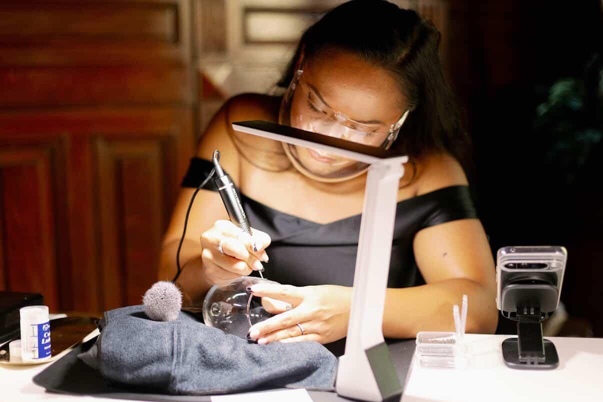Tiffany, live engraver and owner of SLM & Design Co., engraving glassware as personalized guest favors at a wedding reception at The Belvedere in Baltimore, MD.